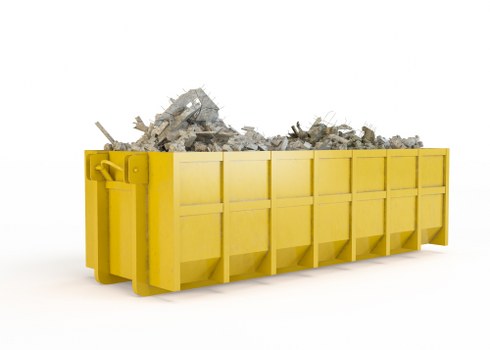 A large, bright yellow skip bin filled with a pile of mixed construction debris, including broken concrete, bricks, and rubble, situated on a white background. The skip features a sturdy metal structure with reinforced sides, bolted panels, and a smooth, painted finish. It is positioned in a way that shows its length, with the debris overflowing slightly at the top, indicating recent use for waste collection. The environment appears to be a clean, indoor or studio setting without any surrounding objects or background context, emphasizing the focus on the skip and its contents. This image reflects the type of waste management service provided by Commercial Waste Barnet, suitable for construction or renovation projects in Barnet or nearby postal areas. The debris's texture varies from rough and jagged to some smoother broken surface fragments. Overall, the scene highlights an efficient method for rubbish removal and disposal, consistent with commercial waste collection services in London suburban areas.